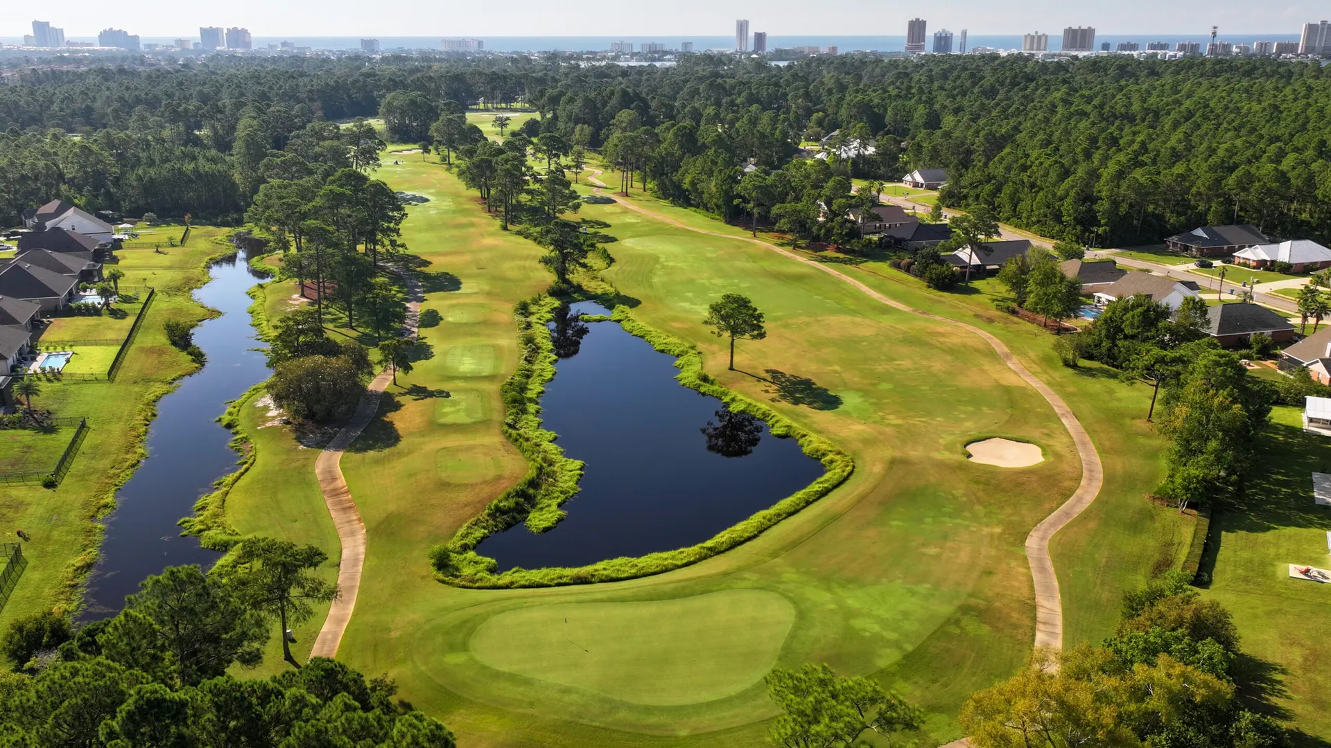 Aerial view of two ponds beside a fairway at Gulf Shores Golf Club, with the skyline in the distance