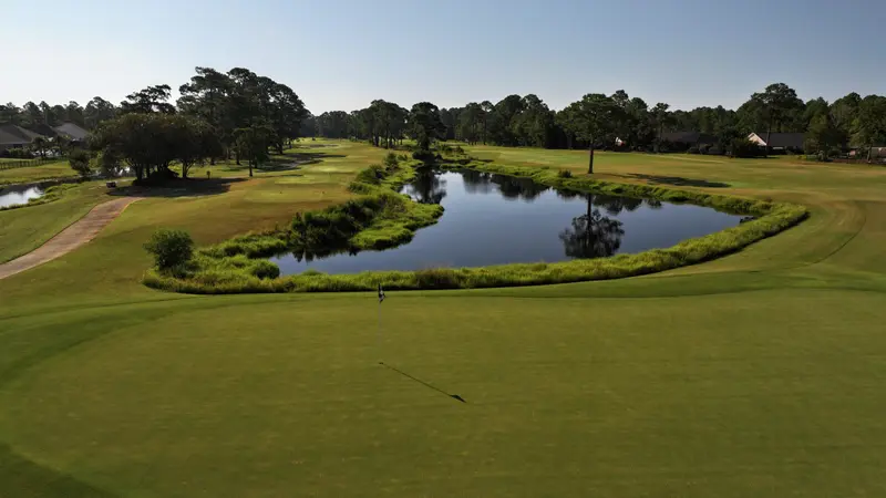 A large green with a horseshoe-shaped pond curving behind it
