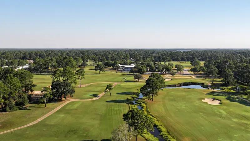 Aerial view of fairways and a bulkheaded creek, with the clubhouse in the distance