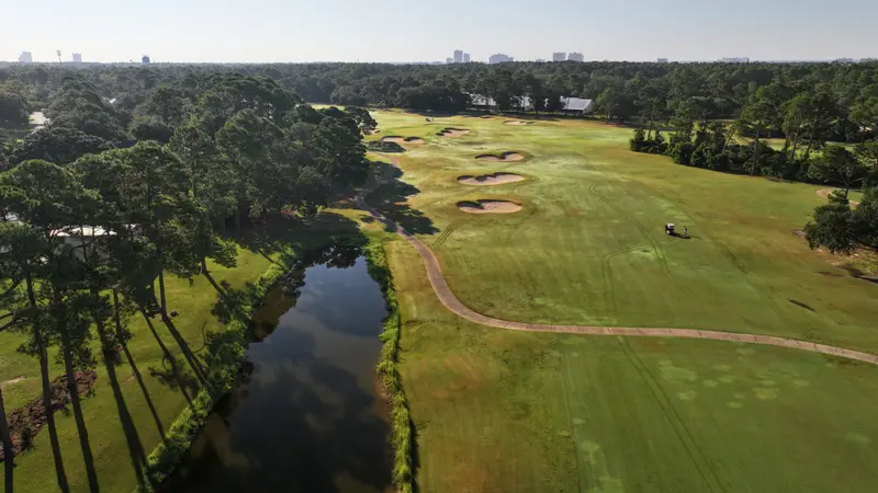 Aerial view of a fairway with a cluster of bunkers and a creek running along the left