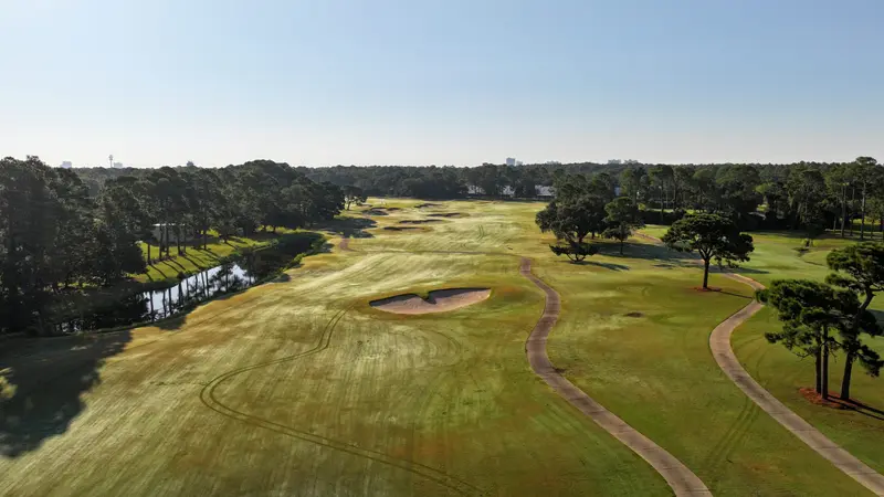 Aerial view of a fairway with a pond along the left and a single bunker in the landing area