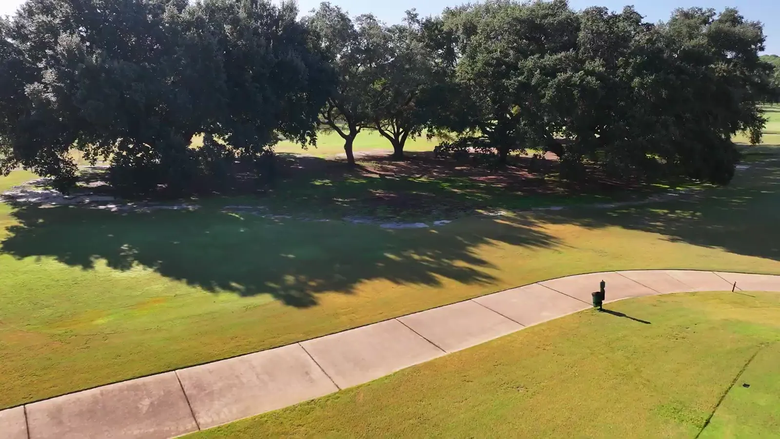 Live oaks casting shade across a fairway beside the cart path at Gulf Shores Golf Club