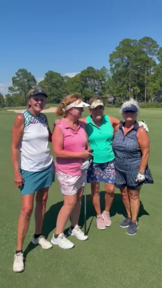 Four women golfers in visors standing together on a fairway at Gulf Shores Golf Club