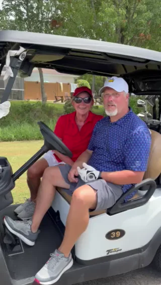 A couple sitting side by side in a golf cart at Gulf Shores Golf Club